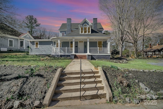 view of front of home featuring a porch, a yard, and a chimney