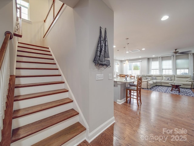 stairs featuring hardwood / wood-style flooring and ceiling fan