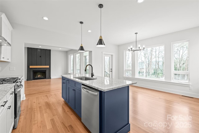 kitchen featuring a fireplace, blue cabinetry, visible vents, appliances with stainless steel finishes, and a sink