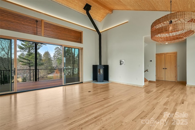 unfurnished living room with high vaulted ceiling, wooden ceiling, light hardwood / wood-style floors, and a wood stove