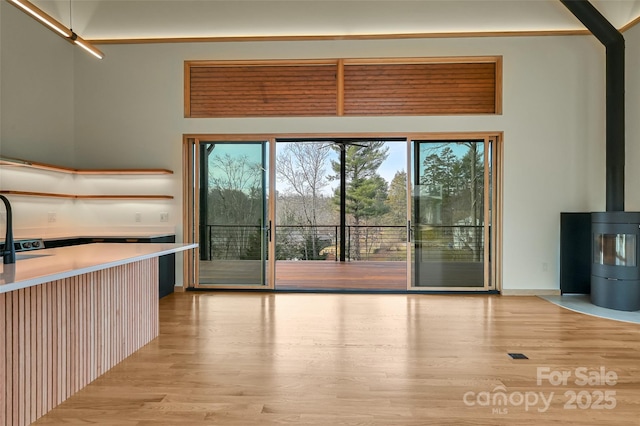 interior space with a towering ceiling, sink, and light hardwood / wood-style floors