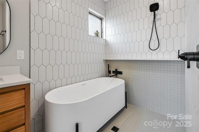 bathroom with vanity, tile walls, and a bathtub