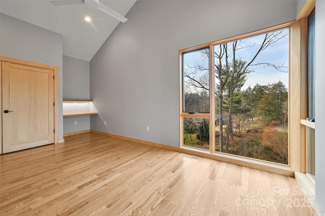 interior space with ceiling fan, a wealth of natural light, built in desk, and light wood-type flooring