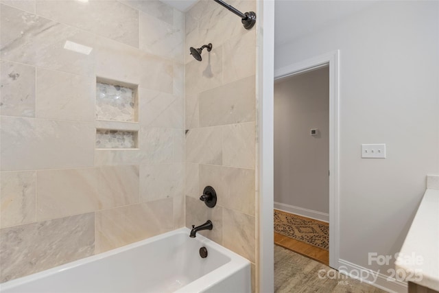 bathroom featuring wood-type flooring and tiled shower / bath