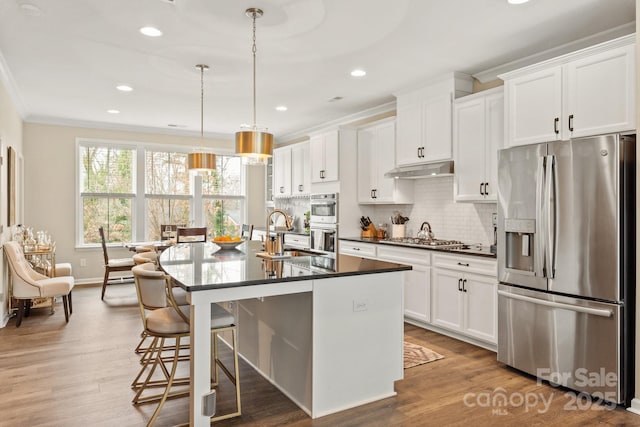 kitchen featuring an island with sink, appliances with stainless steel finishes, sink, and white cabinets