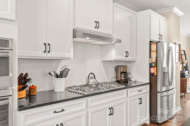 kitchen with appliances with stainless steel finishes, tasteful backsplash, white cabinetry, dark stone counters, and crown molding