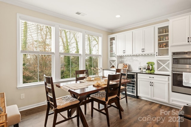 dining area featuring wine cooler, ornamental molding, dark wood-type flooring, and a wealth of natural light