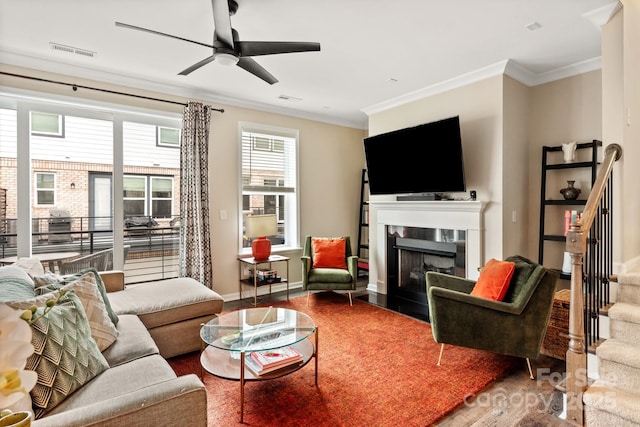 living room featuring ceiling fan, ornamental molding, a high end fireplace, and hardwood / wood-style floors