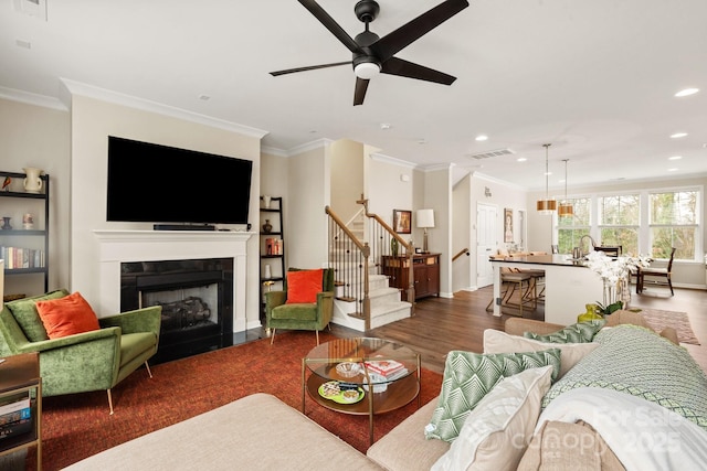 living room featuring dark wood-type flooring, ornamental molding, and ceiling fan