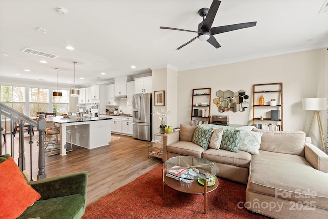 living room featuring crown molding, sink, hardwood / wood-style floors, and ceiling fan