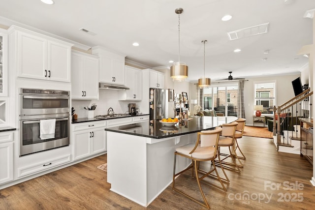 kitchen with a kitchen island, a breakfast bar, decorative light fixtures, white cabinets, and stainless steel appliances