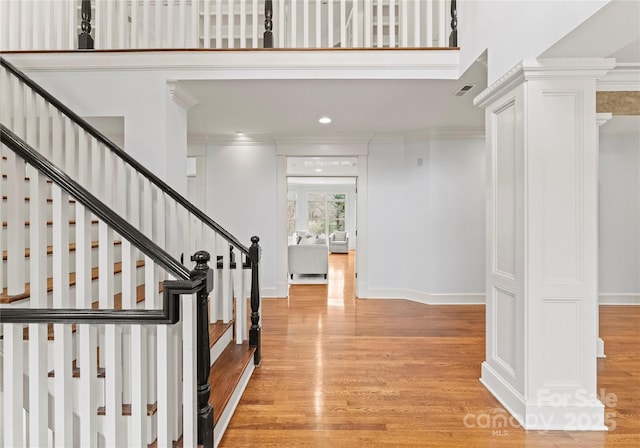 entryway featuring light wood-style flooring, stairs, baseboards, and ornamental molding