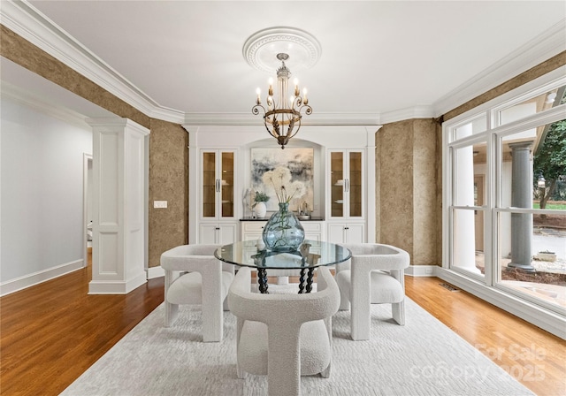 dining space featuring crown molding, wood finished floors, baseboards, and a chandelier