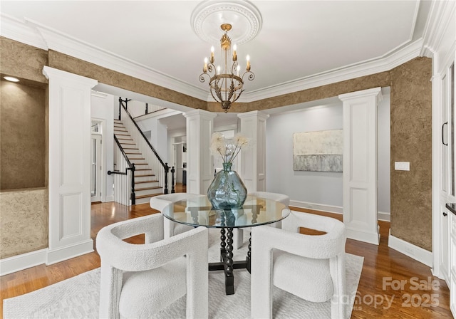 dining area featuring crown molding, a chandelier, stairway, wood finished floors, and ornate columns