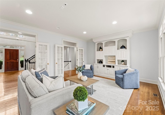 living area with french doors, light wood-type flooring, and ornamental molding