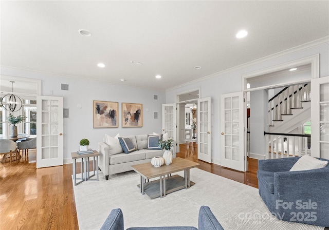 living room with recessed lighting, french doors, an inviting chandelier, and wood finished floors