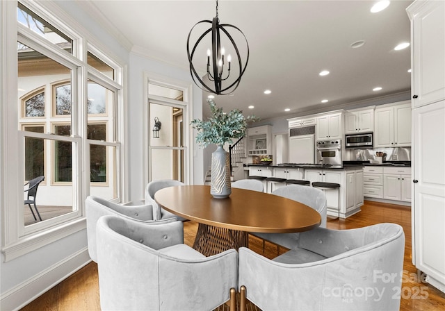 dining area featuring recessed lighting, an inviting chandelier, wood finished floors, and crown molding