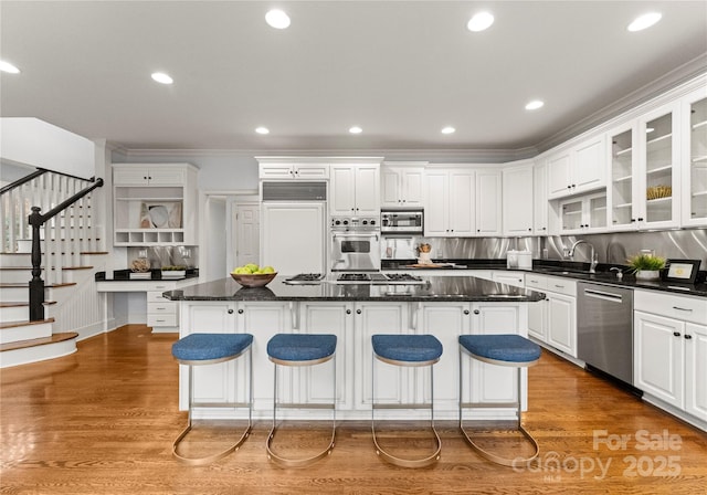 kitchen with wood finished floors, appliances with stainless steel finishes, a kitchen island, and open shelves