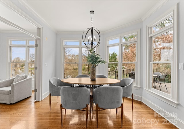 dining room featuring baseboards, light wood-type flooring, crown molding, and an inviting chandelier