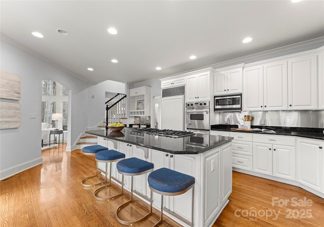 kitchen featuring built in appliances, white cabinets, a center island, and ornamental molding