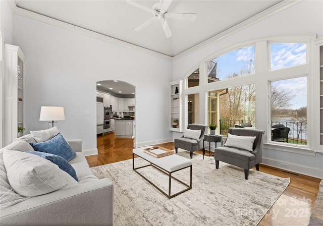 living room with crown molding, a ceiling fan, and wood finished floors