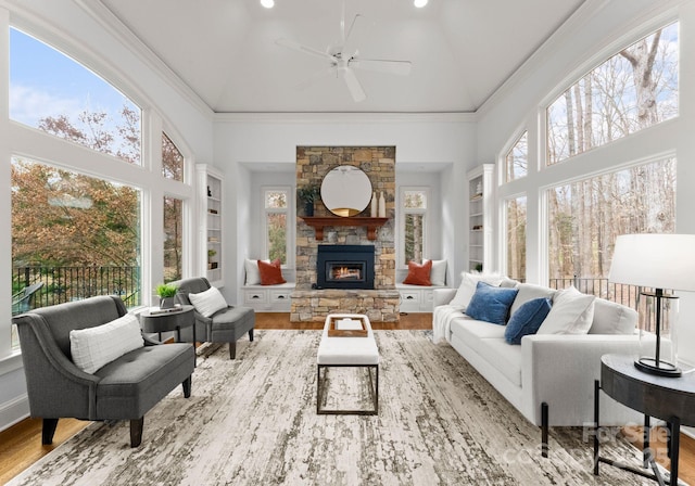 sunroom with a stone fireplace and a ceiling fan