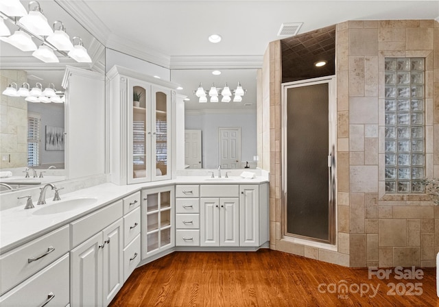 full bath with vanity, wood finished floors, visible vents, tiled shower, and ornamental molding