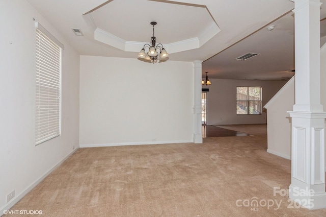 empty room with a raised ceiling, visible vents, light carpet, and ornate columns