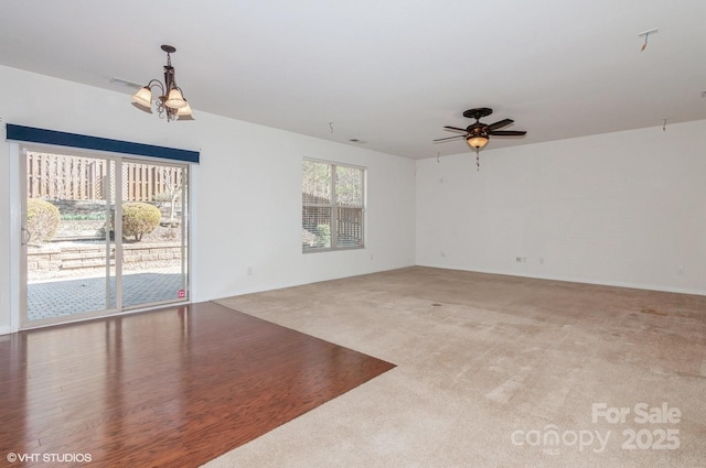 empty room featuring carpet floors and ceiling fan with notable chandelier