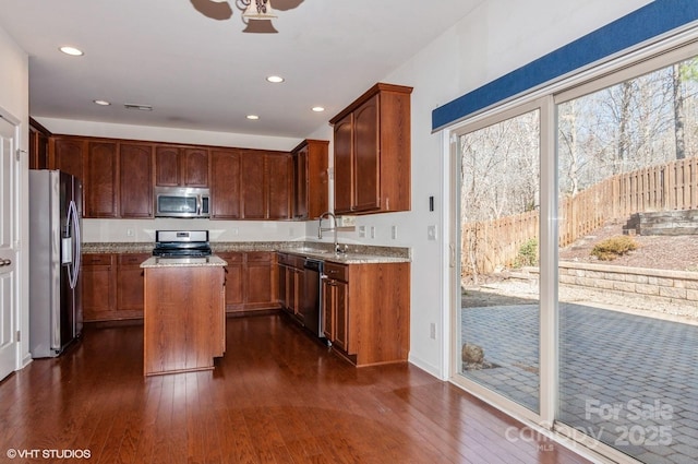 kitchen featuring recessed lighting, stainless steel appliances, a sink, a kitchen island, and dark wood finished floors