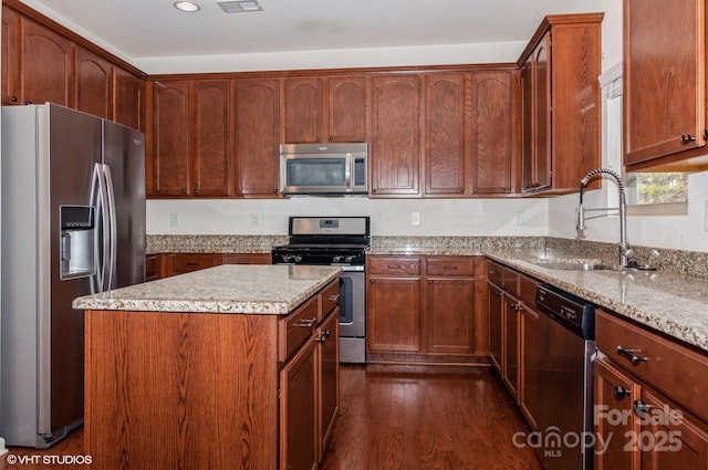 kitchen with a kitchen island, brown cabinets, dark wood-style flooring, stainless steel appliances, and a sink