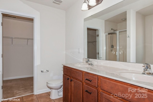 bathroom featuring a walk in closet, visible vents, a sink, and tile patterned floors