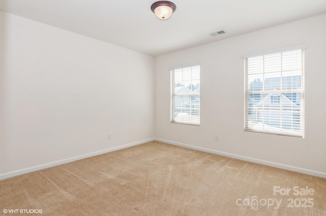 spare room with light carpet, visible vents, and baseboards