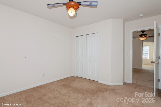 unfurnished bedroom with a ceiling fan, a closet, light colored carpet, and baseboards