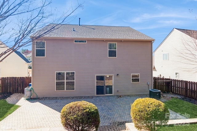 rear view of property with roof with shingles, a patio area, a fenced backyard, and central air condition unit