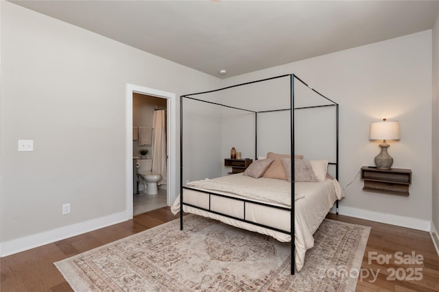 bedroom featuring ensuite bath and dark hardwood / wood-style floors