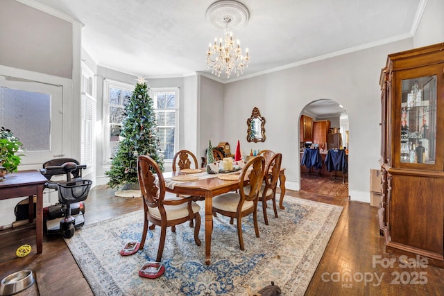 dining area with dark wood-type flooring, crown molding, and a notable chandelier