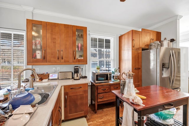 kitchen with sink, light wood-type flooring, ornamental molding, and appliances with stainless steel finishes