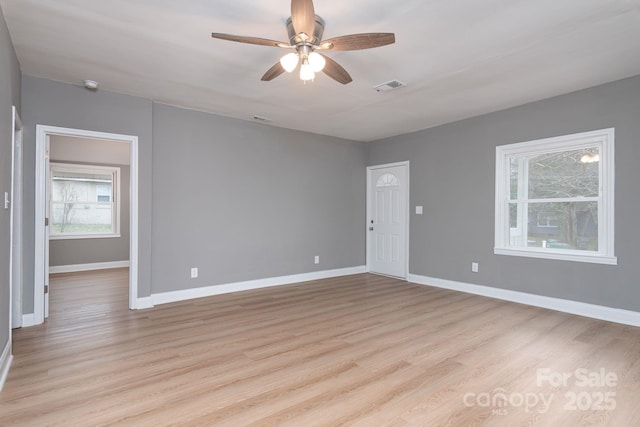 spare room with light wood finished floors, baseboards, and visible vents