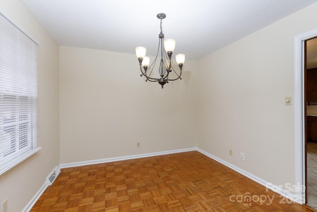 empty room with parquet flooring and a chandelier