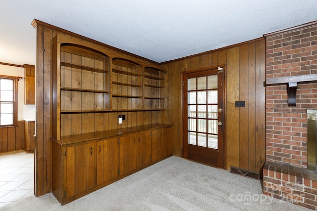 interior space featuring wood walls, crown molding, a textured ceiling, light carpet, and a fireplace