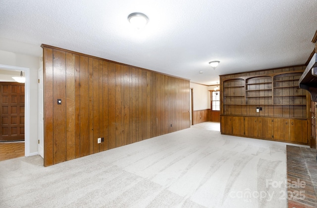 spare room featuring wood walls, light carpet, and a textured ceiling