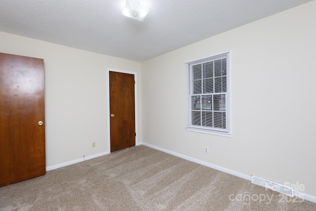 carpeted empty room featuring a textured ceiling