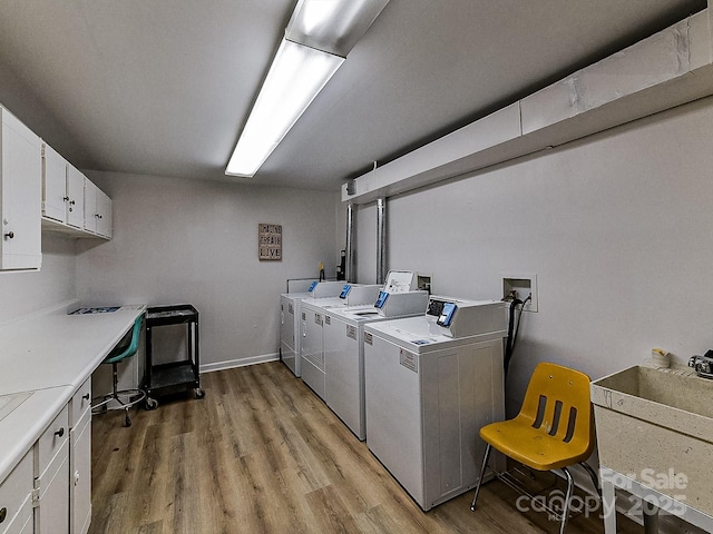 laundry room with sink, light hardwood / wood-style floors, cabinets, and washing machine and clothes dryer