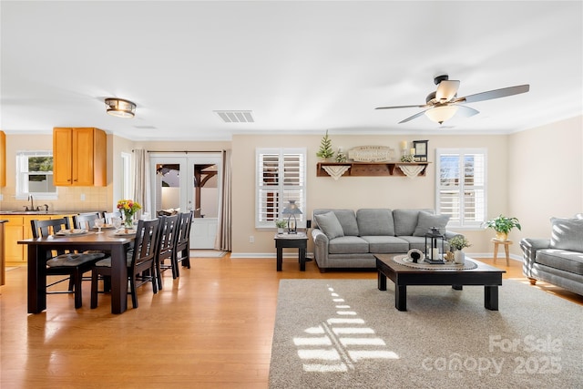 living room with ceiling fan, sink, light hardwood / wood-style floors, and a healthy amount of sunlight