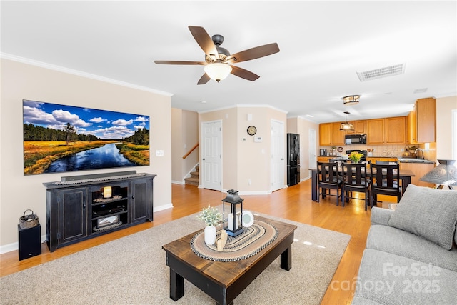 living room featuring sink, ornamental molding, ceiling fan, and light hardwood / wood-style flooring