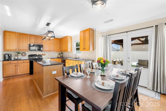 kitchen featuring pendant lighting, a kitchen island, light hardwood / wood-style floors, black appliances, and french doors