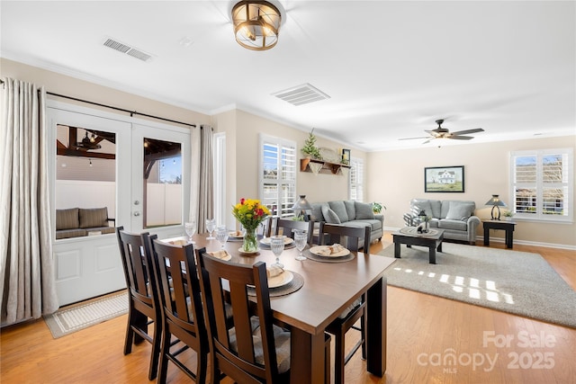 dining space with ceiling fan, light wood-type flooring, crown molding, and french doors