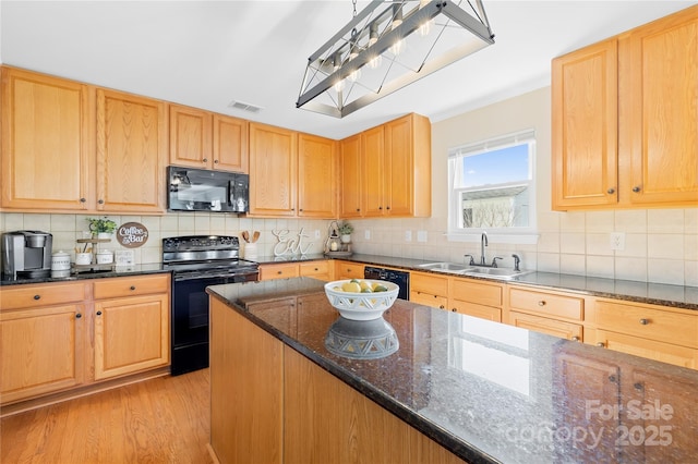 kitchen with sink, dark stone counters, light hardwood / wood-style floors, black appliances, and tasteful backsplash