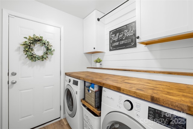 washroom with independent washer and dryer, cabinets, and light wood-type flooring